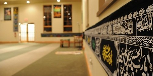 Interior wall hung with black banners bearing Arabic calligraphy