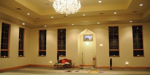 The prayer hall with a chandelier and tall arched windows